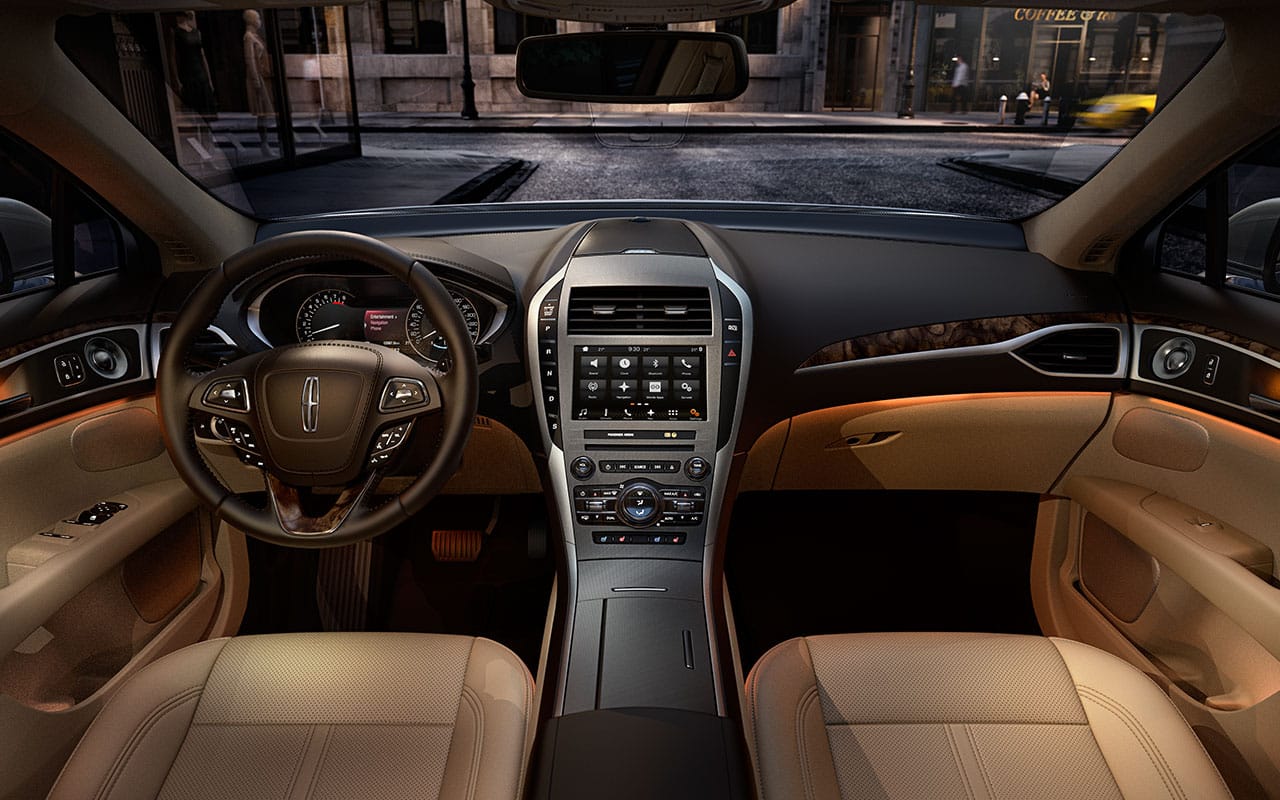 Interior view of a luxury Lincoln vehicle showcasing a sleek dashboard, modern control panel, comfortable leather seating, and ambient lighting features, set against a city street backdrop.
