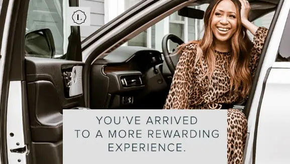 Woman smiling while seated in a car, wearing a leopard print outfit, conveying luxury and enjoyment.
