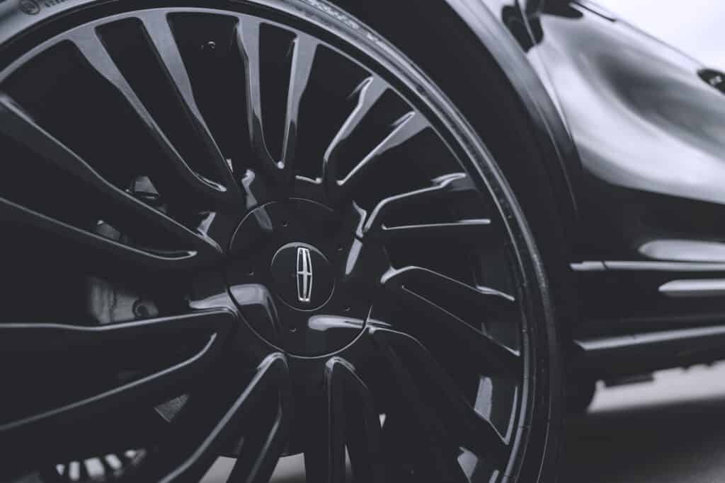 Close-up of a stylish black alloy wheel from a luxury Lincoln vehicle, showcasing its sleek design and intricate spoke pattern against a blurred background.