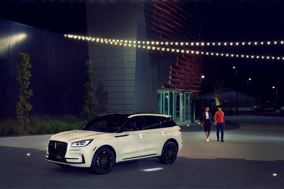 Luxurious black SUV parked in a lush, green forest setting, highlighting its sleek design and elegance.