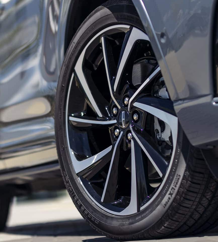 Close-up of a sleek black and silver alloy wheel on a modern car, showcasing luxury design.