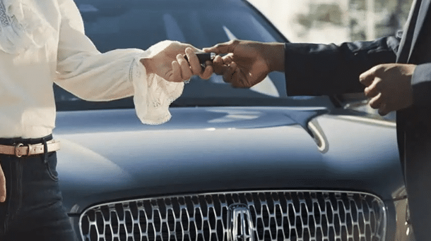 Exchanging car keys in front of a luxury vehicle, symbolizing luxury car delivery service.